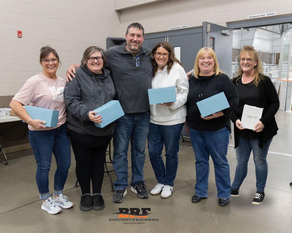 Six staff members standing in a row, holding boxes