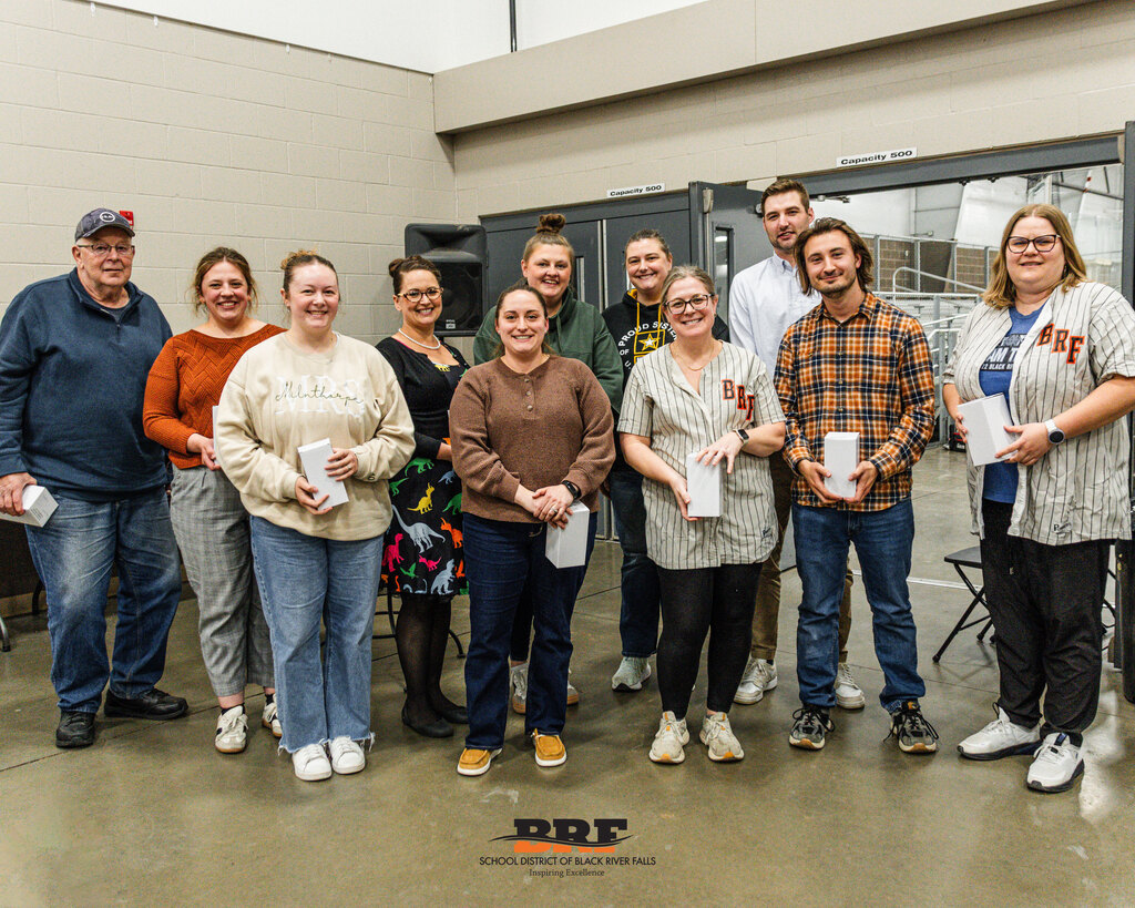 Group of people standing in two rows, holding boxes.