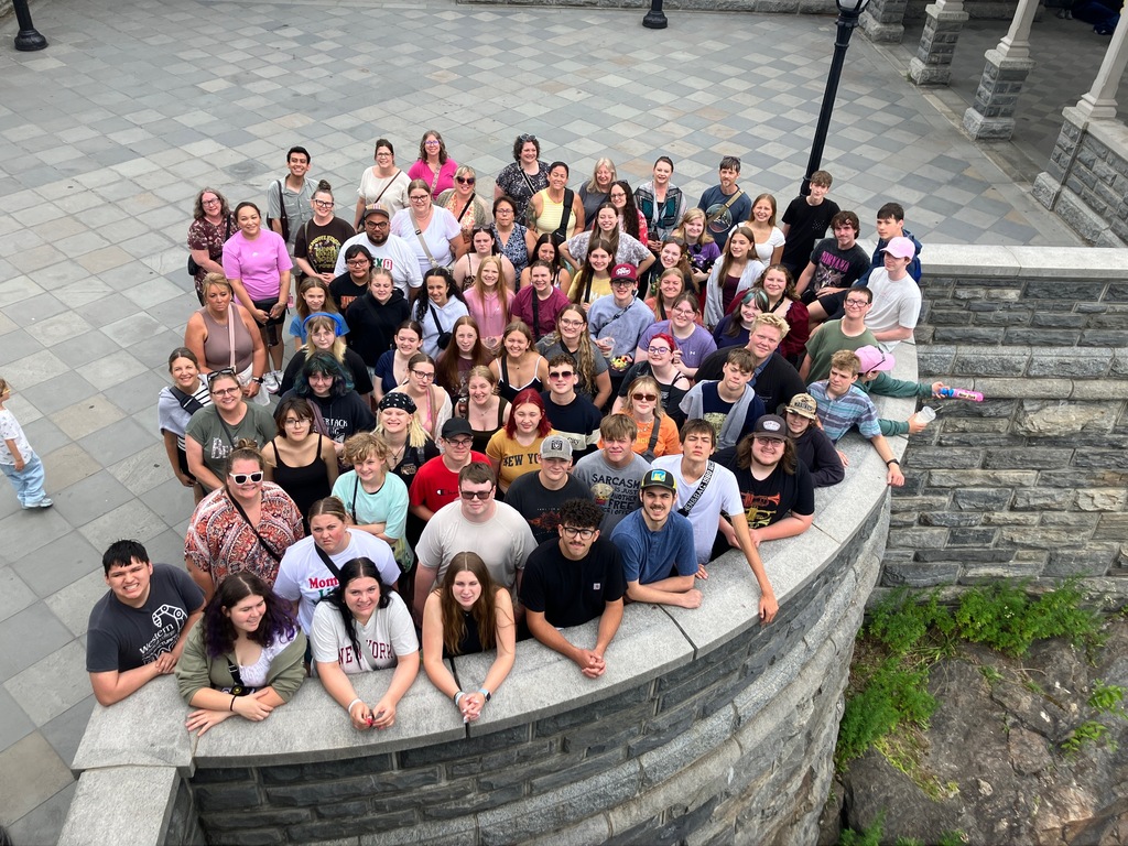 Large group of people standing in a group look up at camera