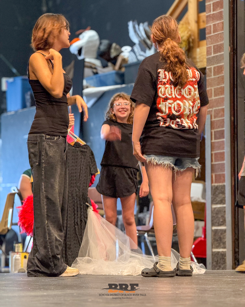 Three students interacting on the stage.