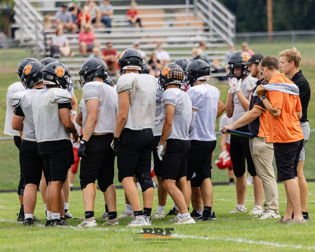 Football players circle up on field.