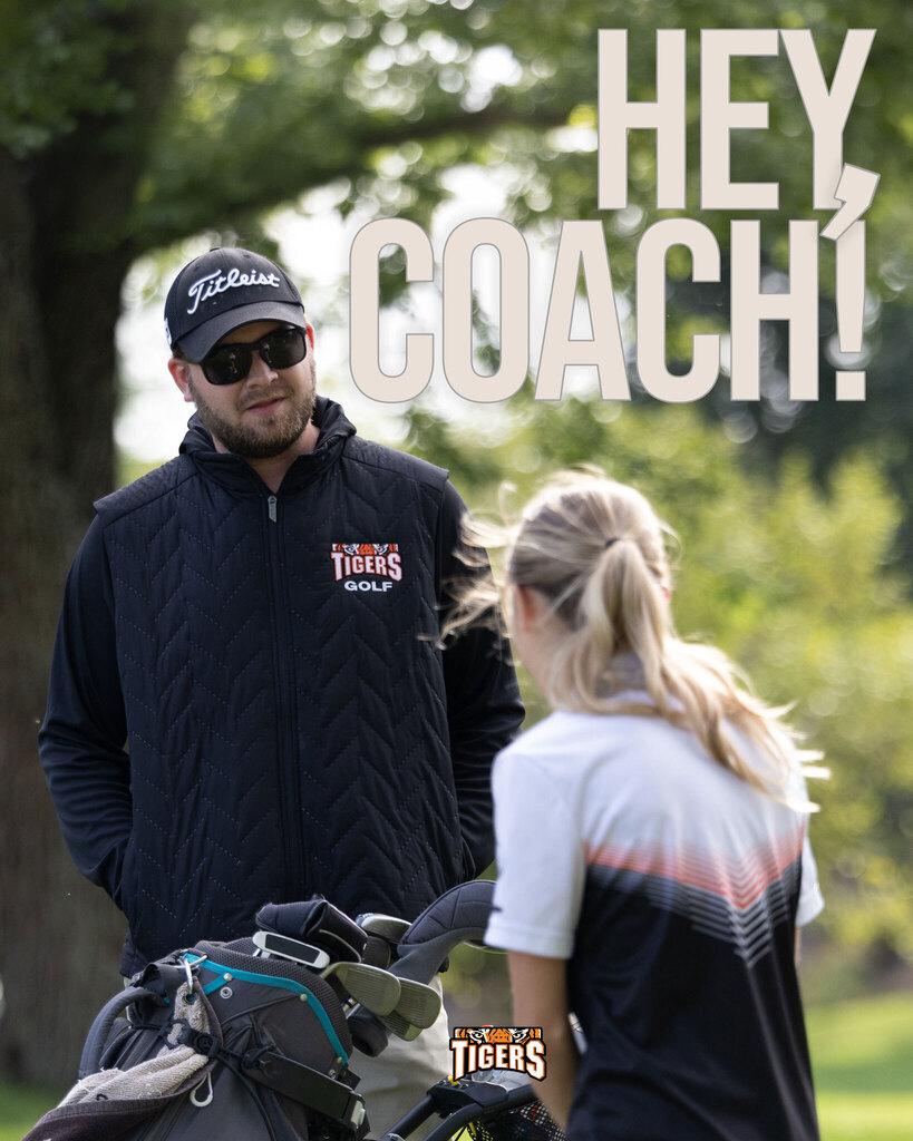 A graphic titled "HEY, COACH!" in large light gray text against a green outdoor background. A Black River Falls Tigers golf coach wearing a black Titleist hat, sunglasses, and a black vest with "TIGERS GOLF" on the chest stands smiling next to his golf bag while speaking with a female student-athlete. The Tigers logo is featured at the bottom center.