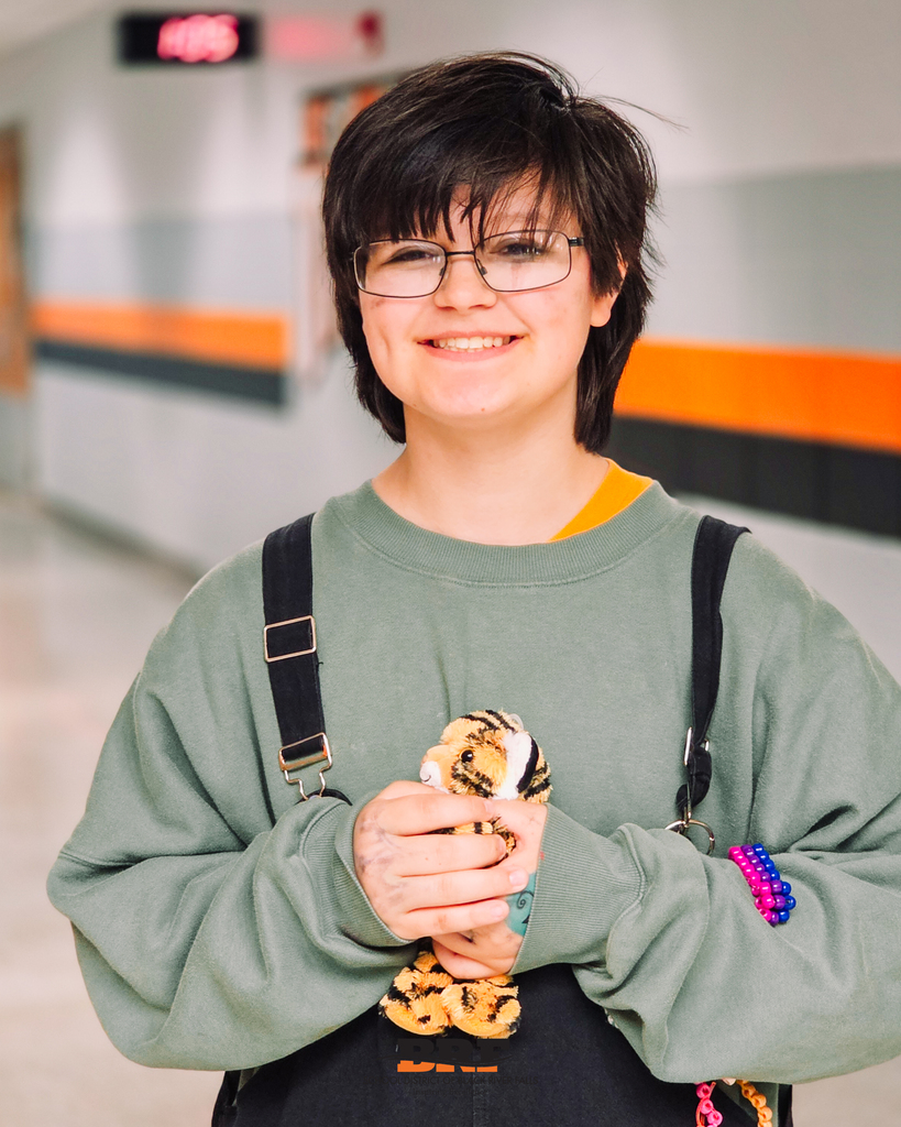 Students smiles while holding stuffed tiger