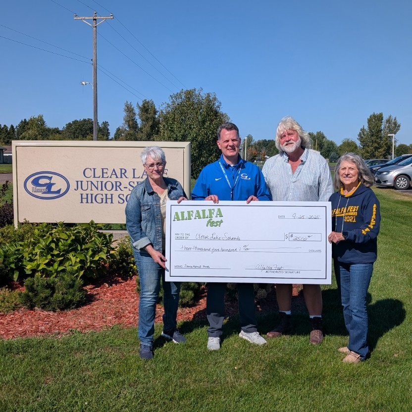 three adults holding a giant donation check
