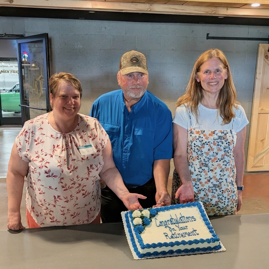 3 retirees posing behind a cake