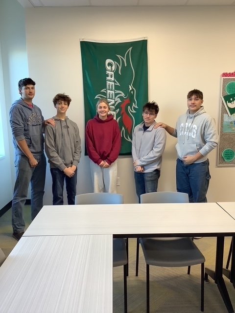 Alt text: “Five Florence High School students stand together in a classroom next to a green UW–Green Bay Phoenix banner. They are smiling and dressed casually in sweatshirts and jeans. The photo celebrates students earning college credits through UW–Green Bay programs, symbolizing academic achievement and school pride.”
