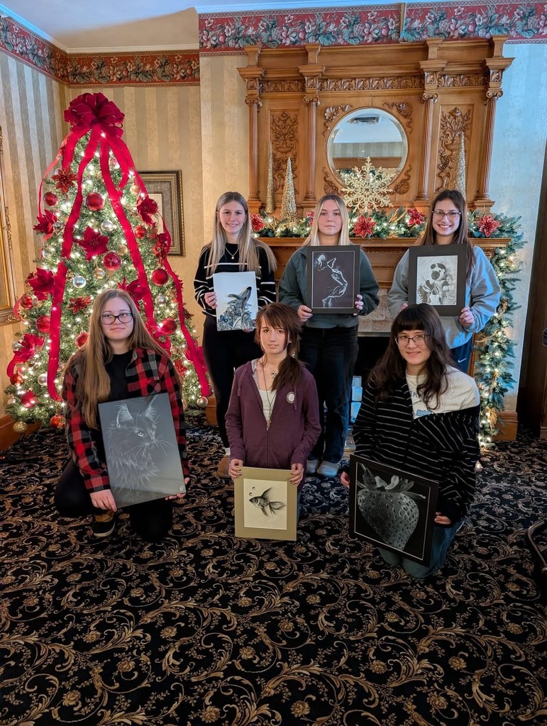 Area Asa winners with their art pieces next to a christmas tree covered in Red ribbon