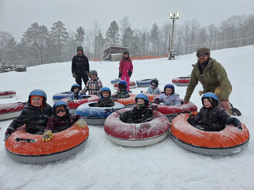 4k Students in snow tubes with volunteers on the bottom of the ski hill