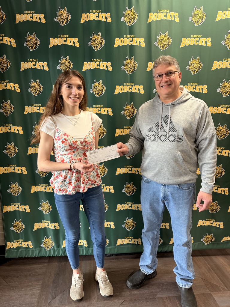 Madison Aubuchon on accepting the Gloria Jean Merhalski Perseverance & Trade Scholarship from Darren Merhalski in front of a green bobcat background