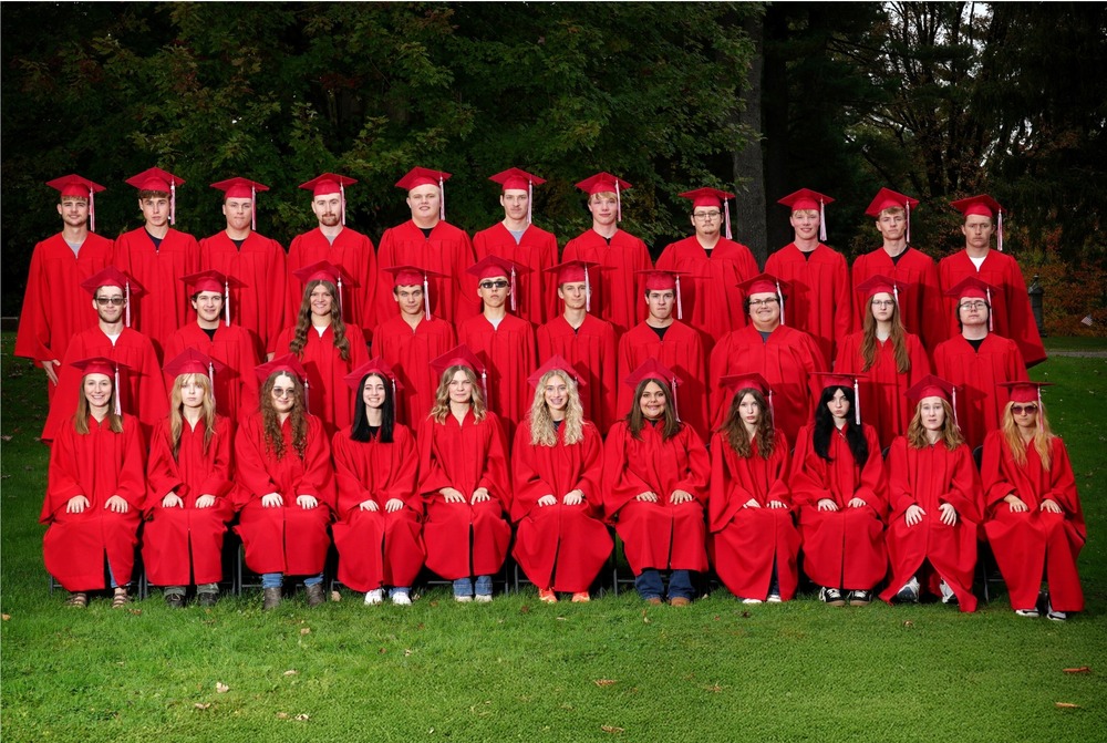 large group of students in cap and gowns outside on green grass