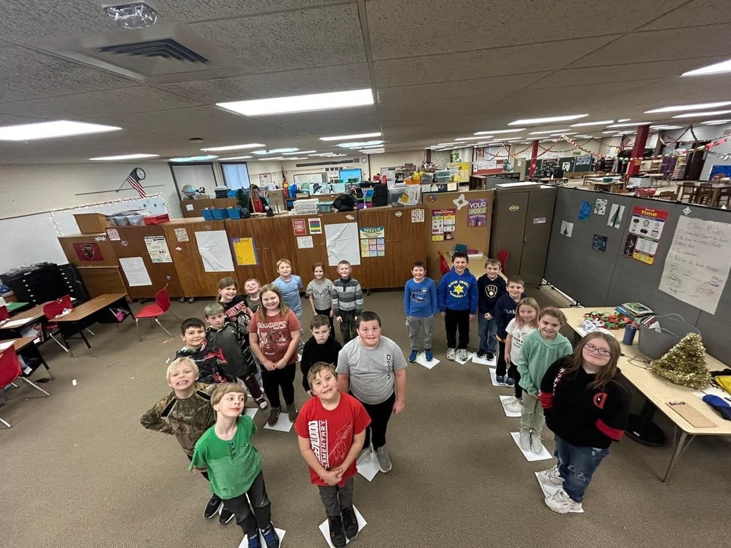 children standing in a classroom forming the number 67