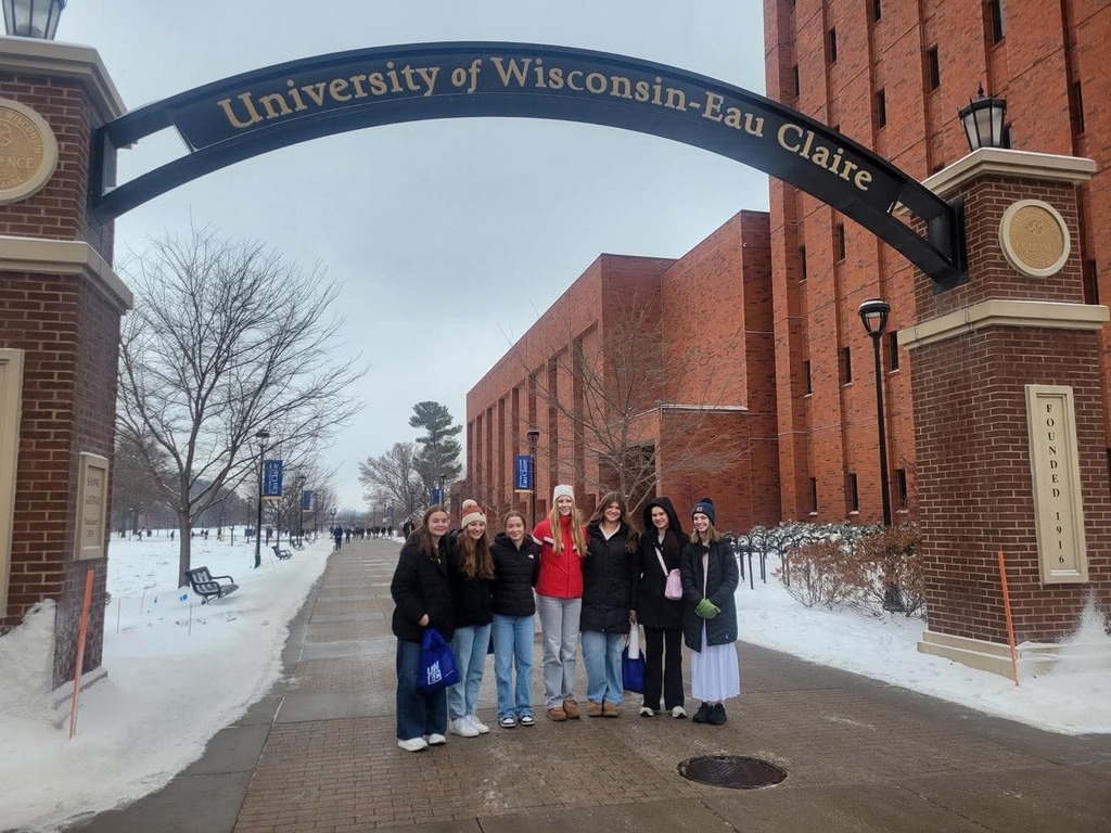 snow, brick building, students standing under and arch