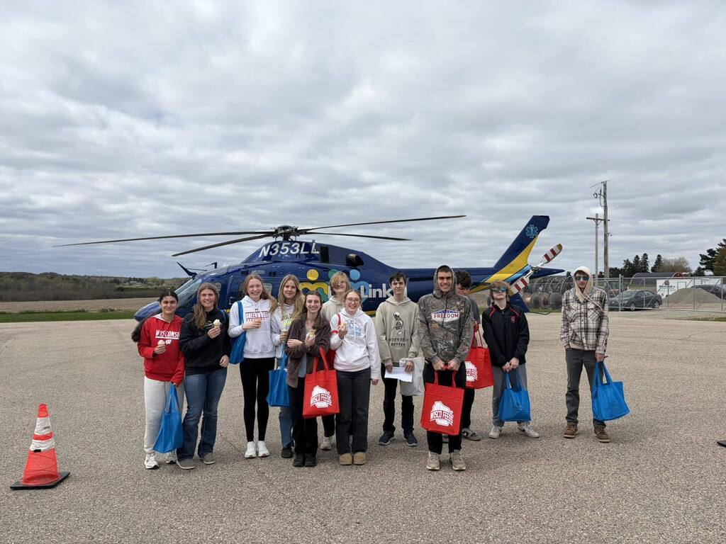 students standing in a row in front of a helicopter