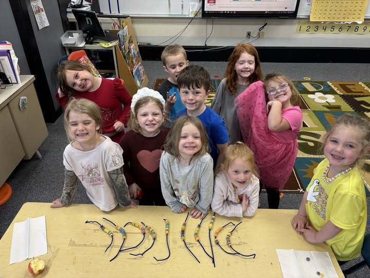 Students standing in a classroom behind a table