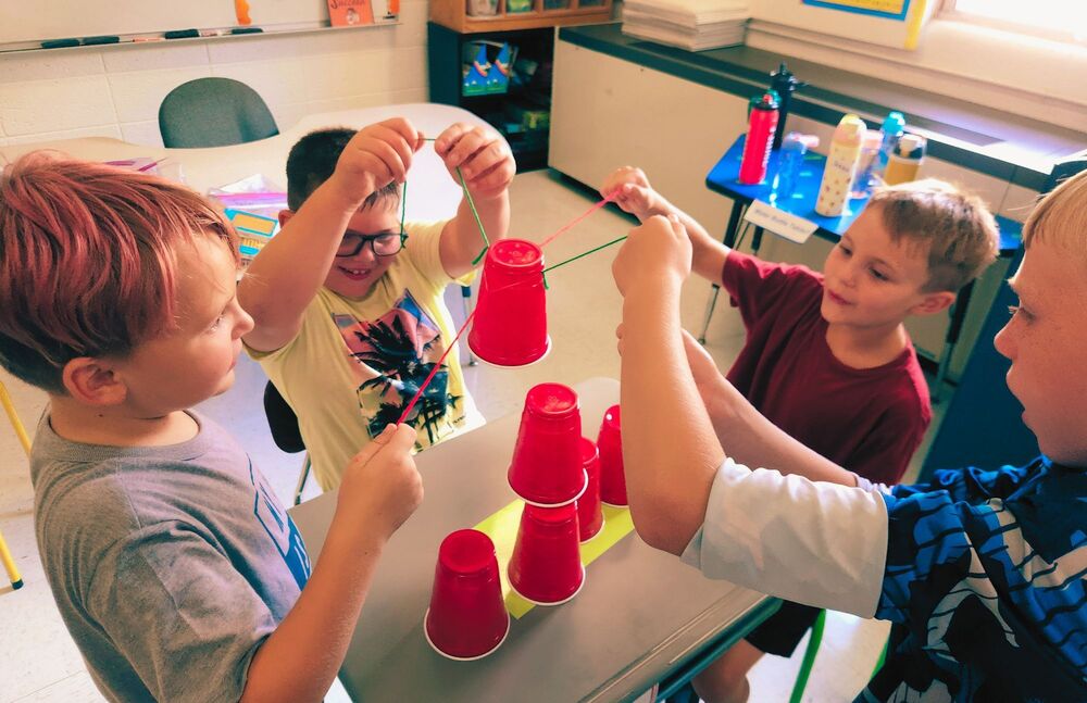 Elementary students do team building exercise with cups