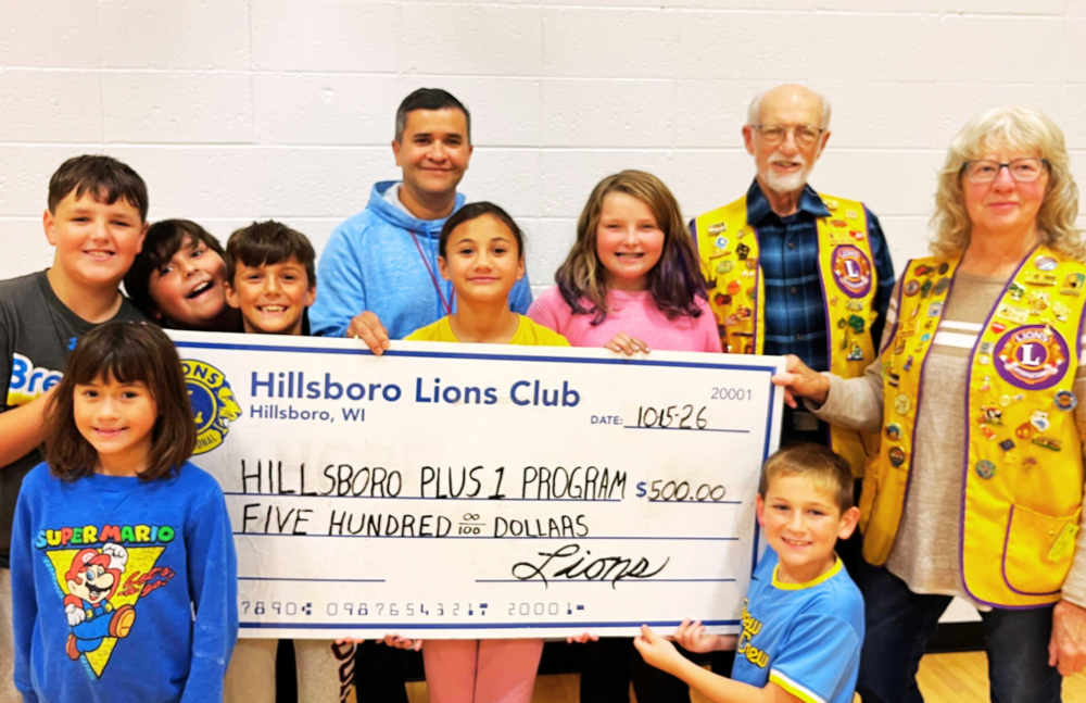 Students stand with Plus One donation check