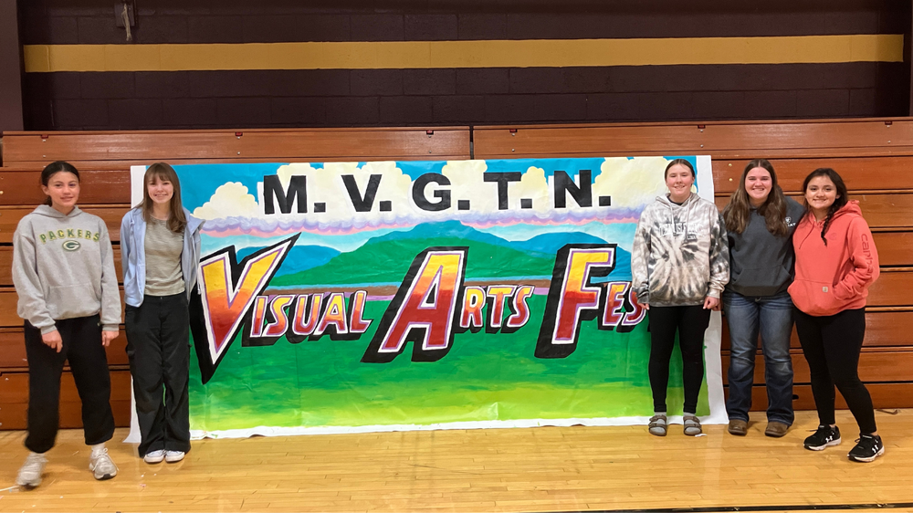 Hillsboro students pose next to Visual Arts Fest poster
