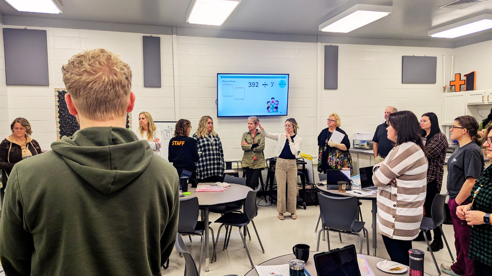 Staff stand with instructor who demonstrates new math practices