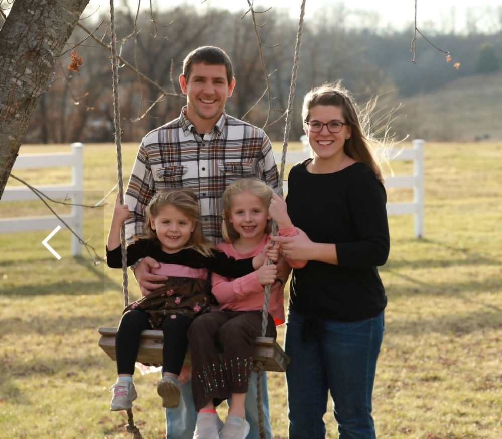 New staff member posing with children on swing and husband