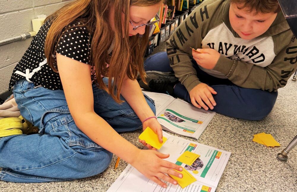 Students sit on ground playing fraction games