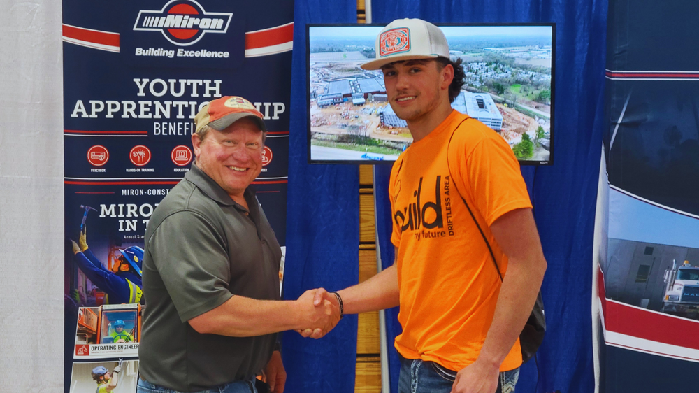 Student shakes hands with Miran Employee