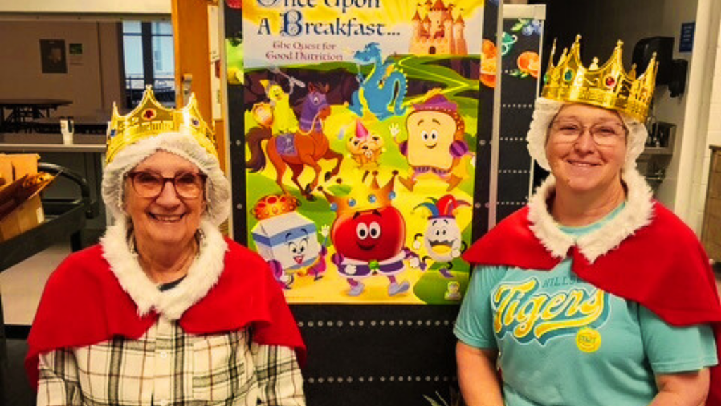 two food service workers pose in crowns and royal attire