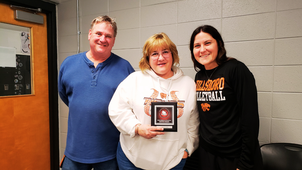 Jill and Bob Stekel pose with Hilary Stanek, athletic director, to receive an award.