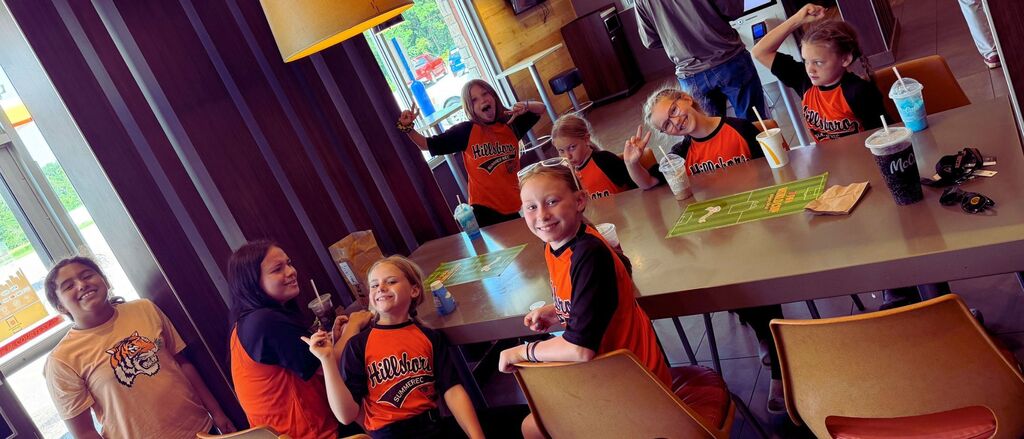 Summer minor league players gather around a table at McDonalds, smiling