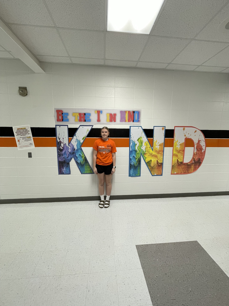 student wearing orange, posing with Kind sign