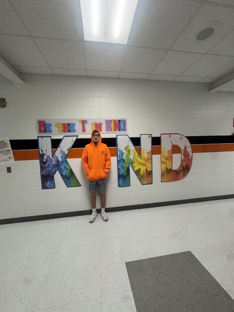 Student wears orange, poses with Kind sign.