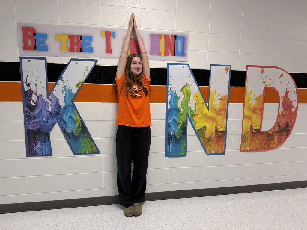 Student wears orange, poses with Kind sign.