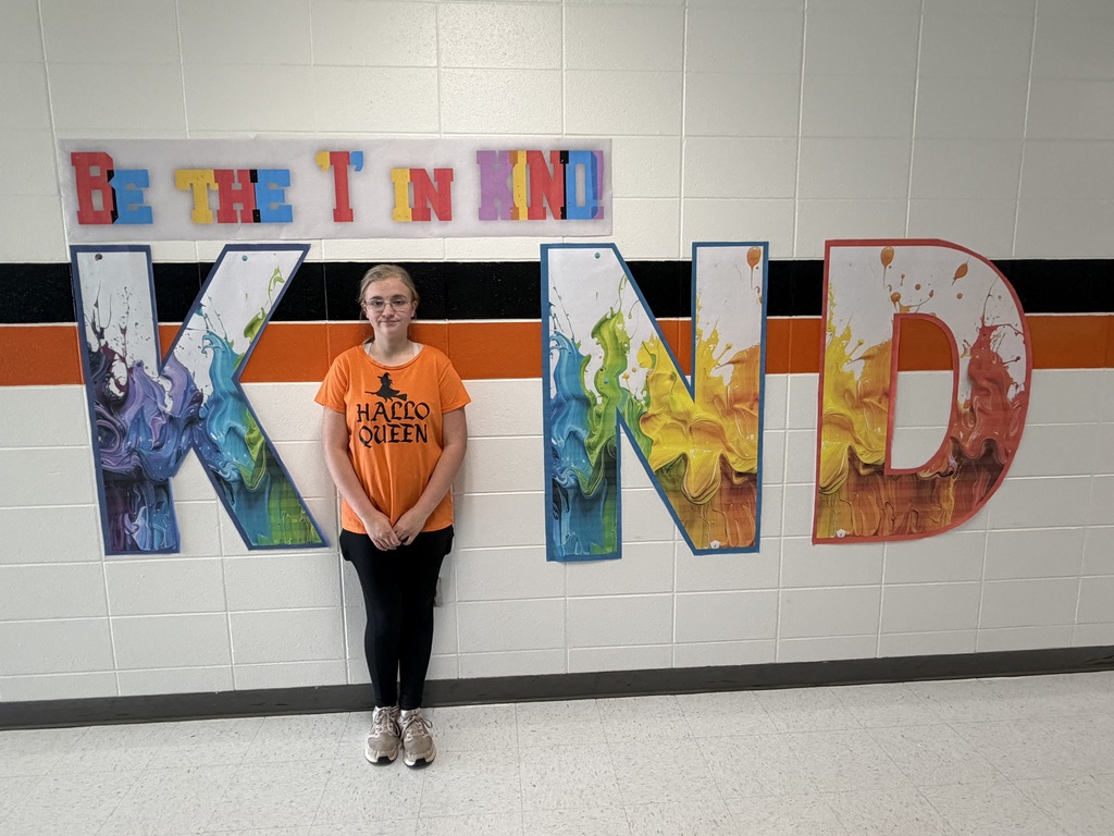 Student wears orange, poses with Kind sign.
