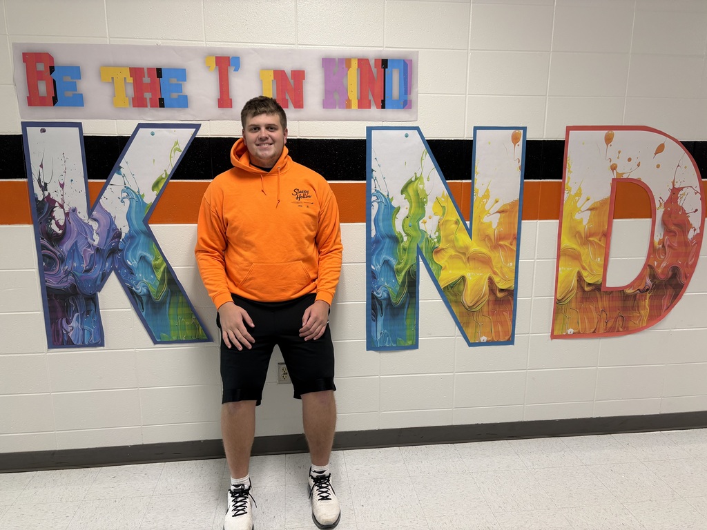 Student wears orange, poses with Kind sign.