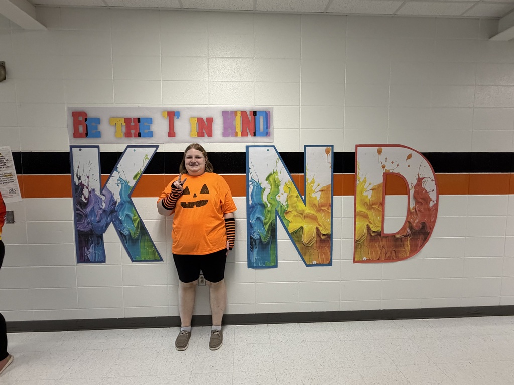 Student wears orange, poses with Kind sign.