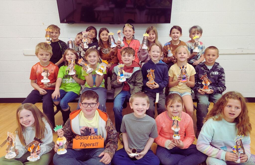 Second graders hold bobble heads they created.
