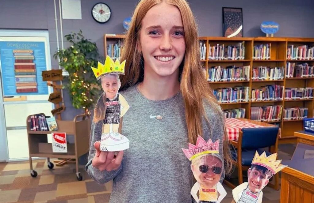 Olivia McCauley poses with bobbleheads of Cross Country 