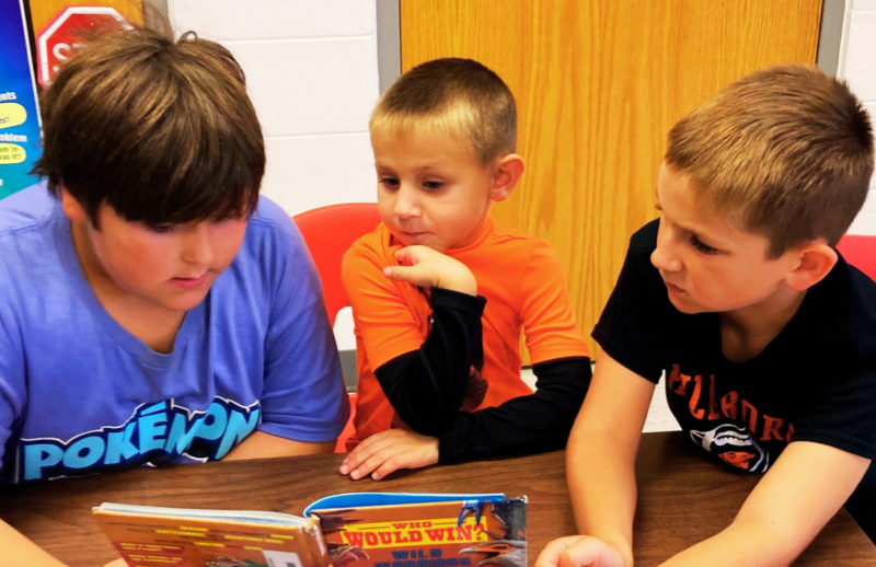 Students gather at a table to read together