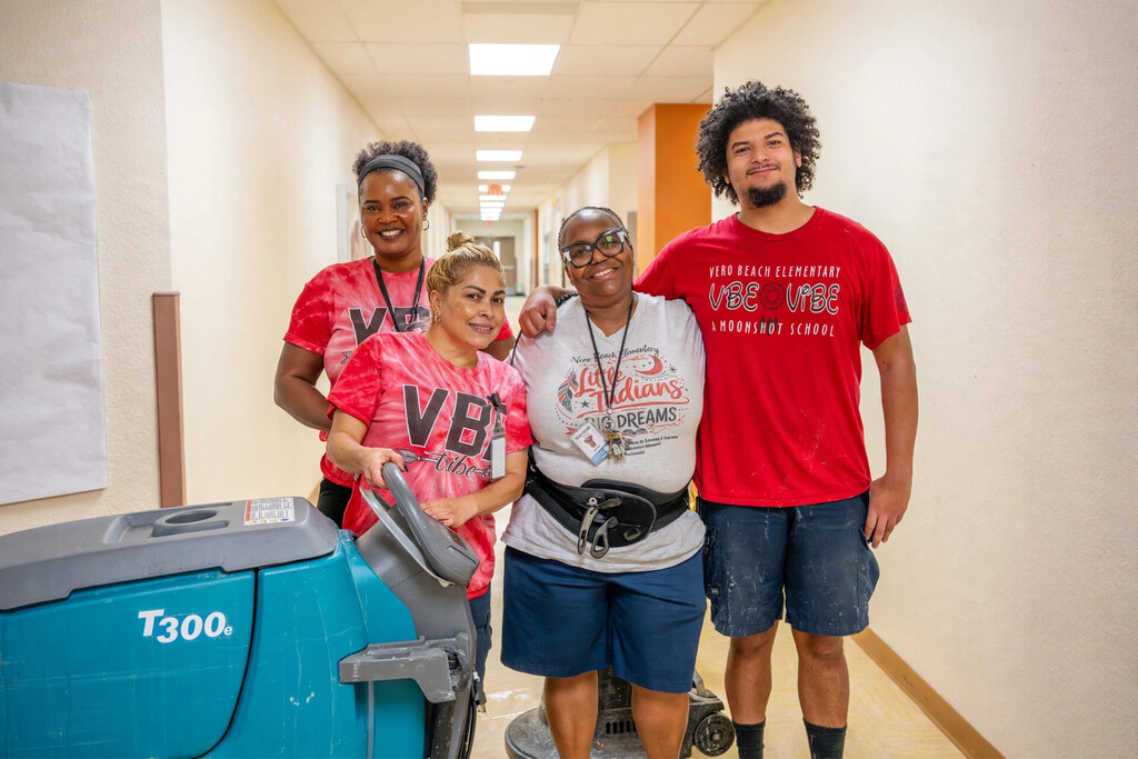 Four smiling custodial team members pose together in a school hallway at Vero Beach Elementary, one holding a floor scrubber. Text on the graphic reads: "National Custodian Appreciation Day. Thank you for all you do. Our custodial teams keep our schools clean, safe, and welcoming. Today we celebrate them.