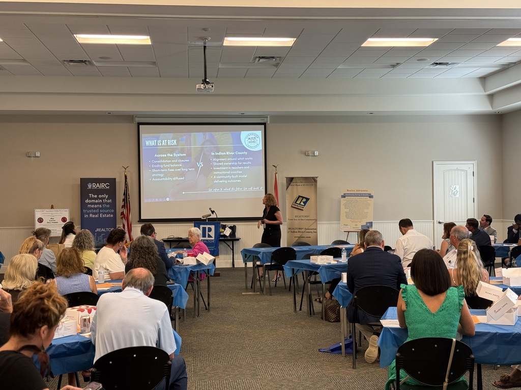 Dr. Christina Jacobs, Chief of Staff for the School District of Indian River County, presents to members of the Realtors Association of Indian River County on October 15, 2026. Attendees are seated at tables as she discusses educational priorities, student success, and community partnerships.