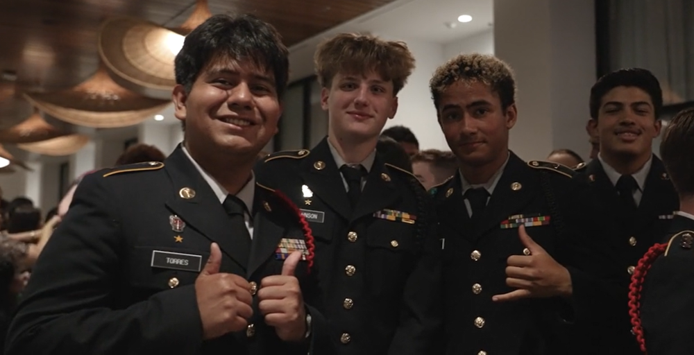 Young men wearing military uniforms while smiling and giving thumbs up