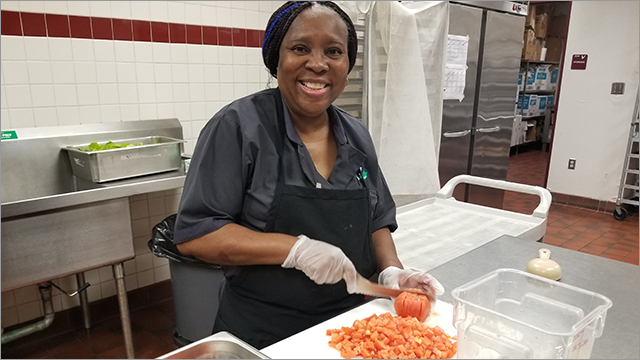 food service worker slices tomatoes