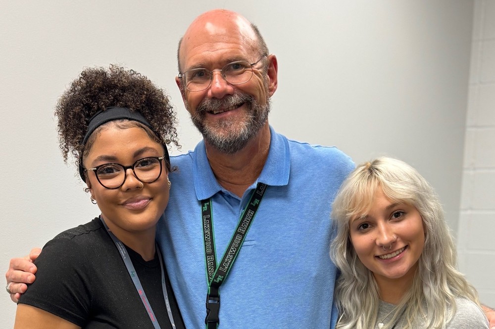 Two students smiling with their teacher.