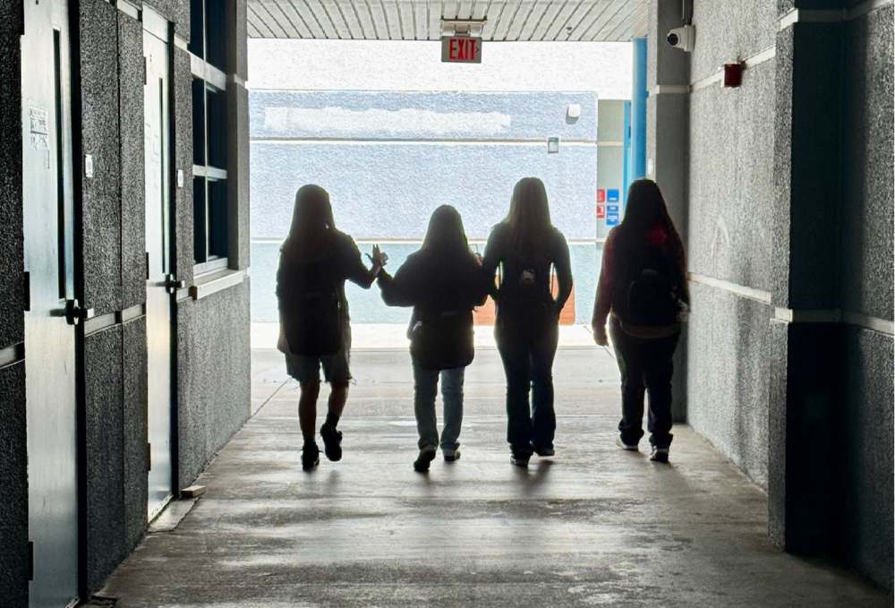 Silhouettes of students walking down a dark high school hallway
