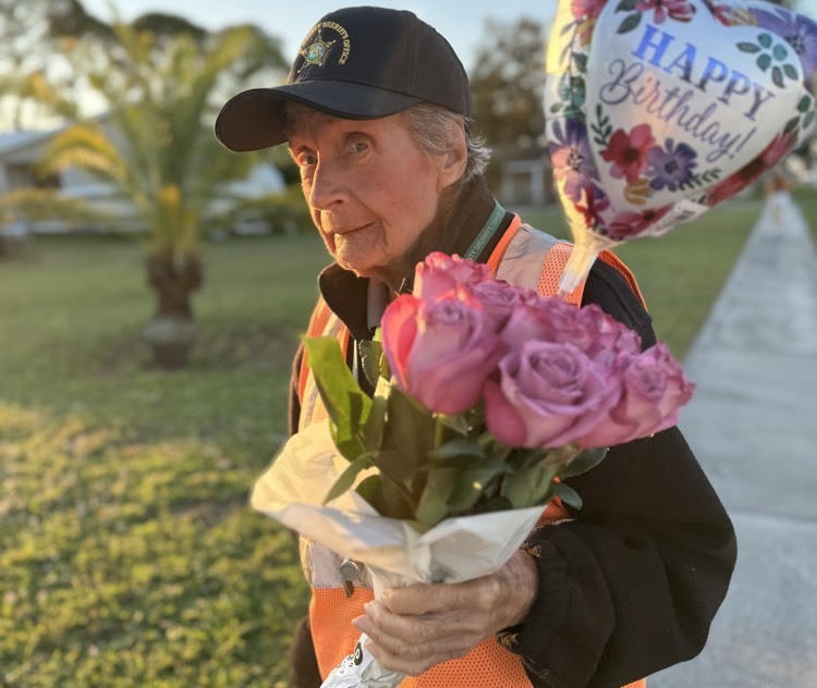 A crossing guard holds pink roses that were gifted to her for her birthday