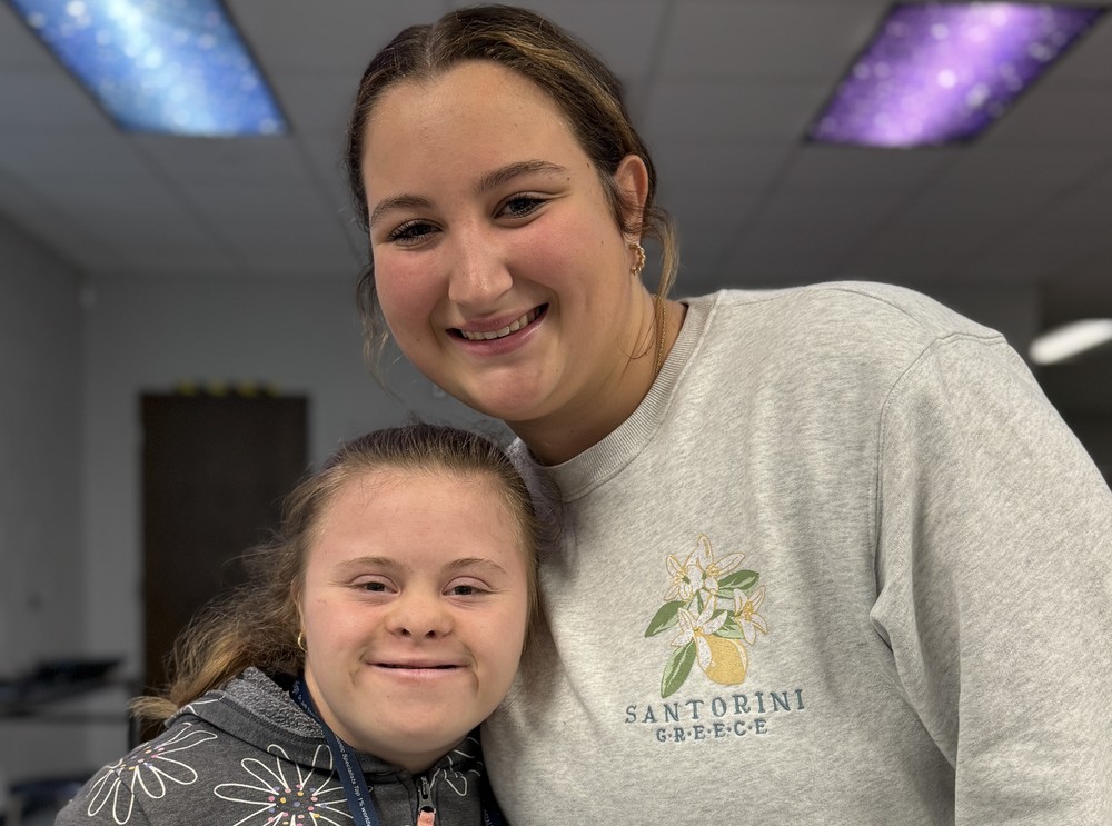 Two students smile inside a high school classroom.
