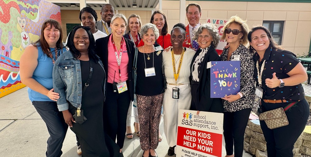 A group of school and community leaders stand together in support of school attendance.