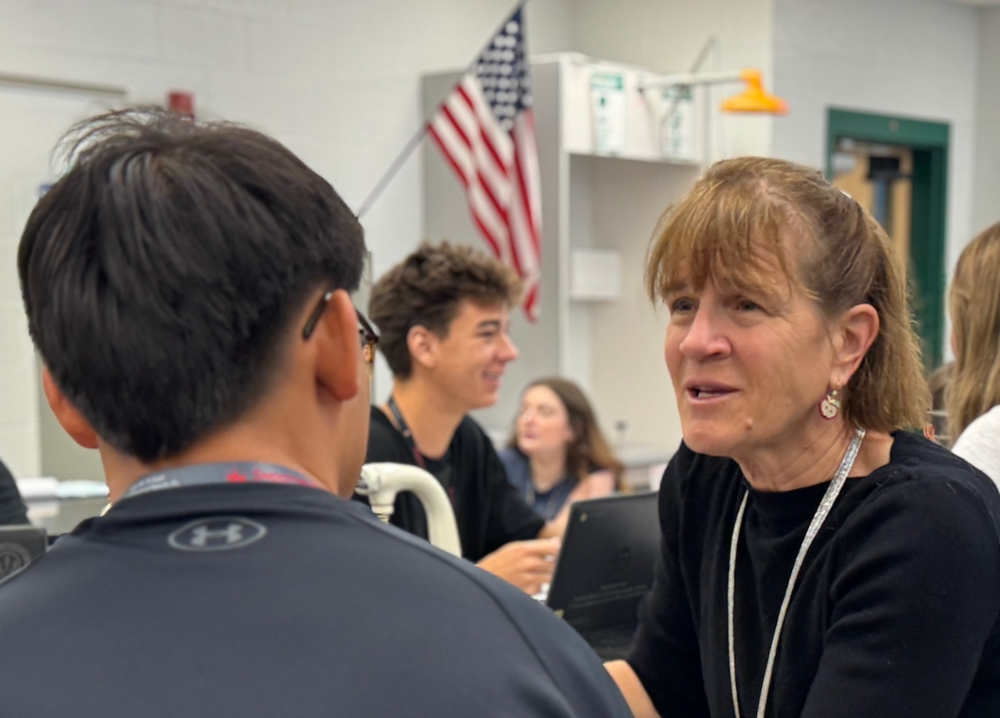 A teacher speaking with a student inside a classroom