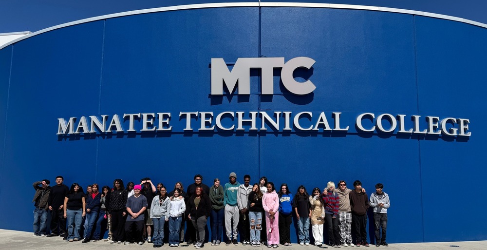 High school students attend a field trip and stand in front of a building that reads, Manatee Technical College.