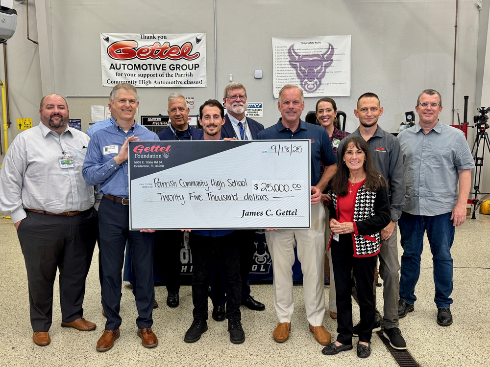 A group of school leaders and Gettel leadership celebrate student success with a large check.