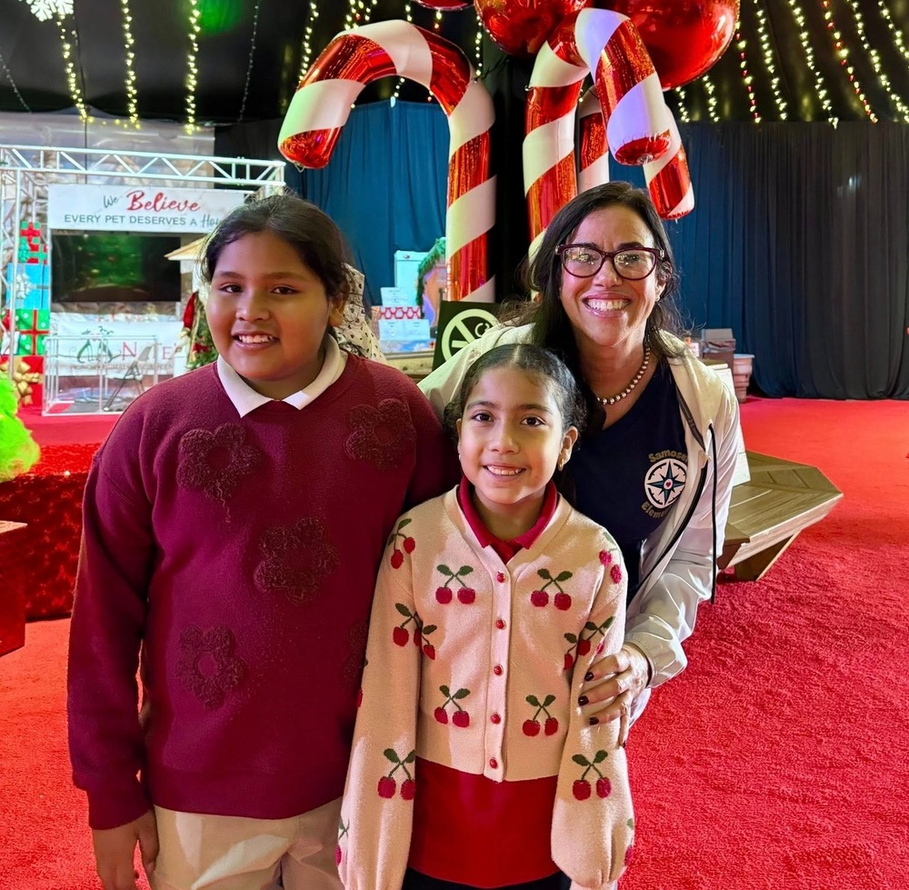 A teacher and two students smiling while standing inside the Big Top at Wonderland UTC.